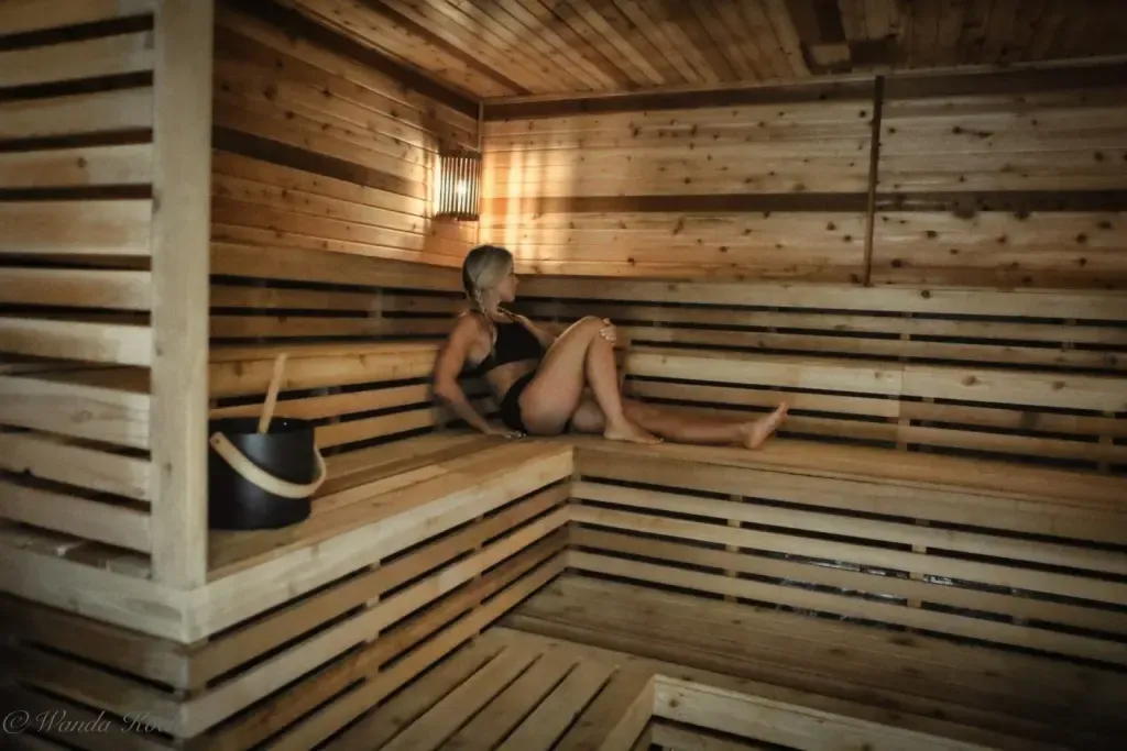 Guest relaxing in the Finnish sauna at Sauna Culture Charlotte with sauna bucket and ladle visible on the lower bench