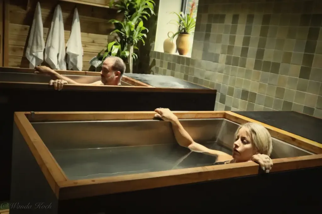 Two guests in side-by-side individual cold plunges — Sauna Culture uses individual tubs at three temperatures rather than a shared communal plunge
