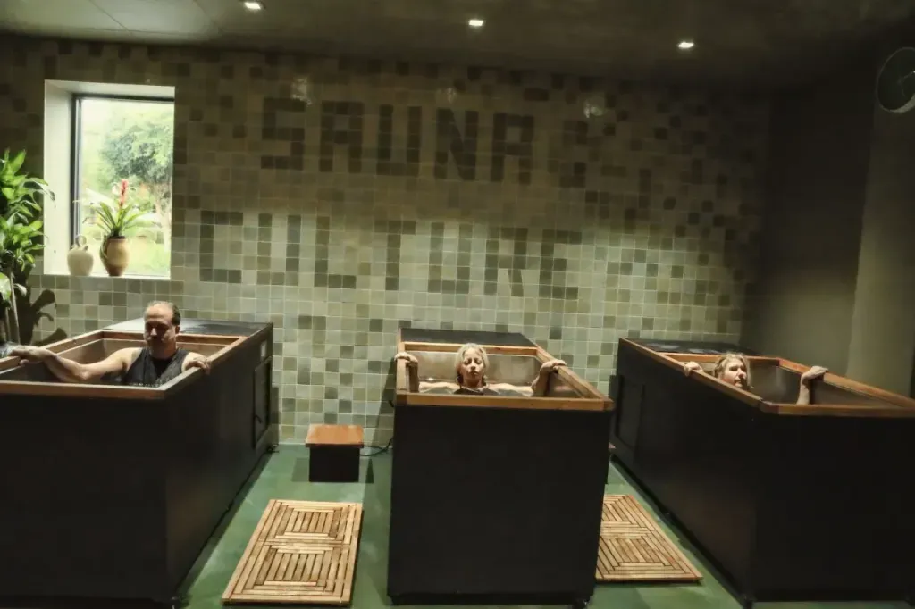 Three individual cold plunges in the Sauna Culture cold-plunge room in Charlotte, with the Sauna Culture tile mural behind them