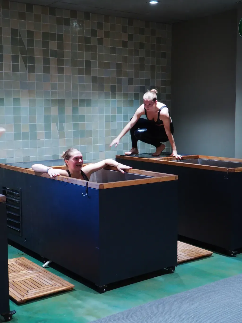 Friends laughing through their first cold plunge together at Sauna Culture Charlotte