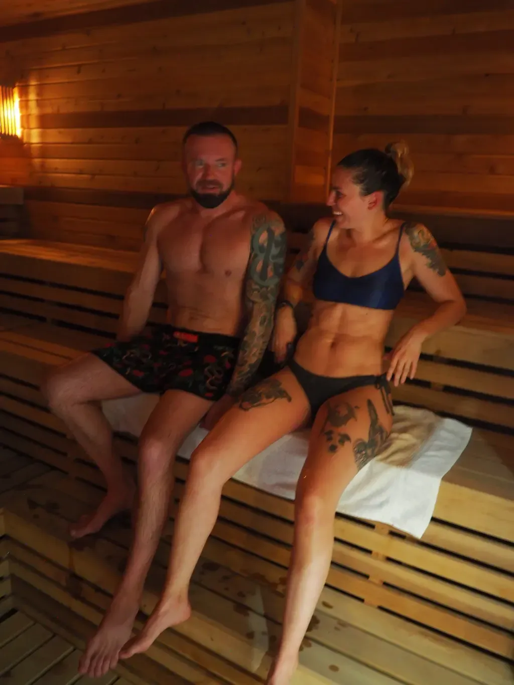 Couple relaxing together on the upper bench of the Finnish sauna at Sauna Culture Charlotte