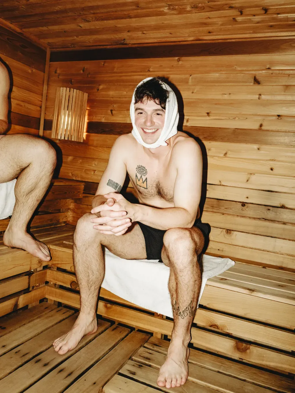 Guest smiling with a towel wrapped around his head in the Finnish sauna at Sauna Culture Charlotte