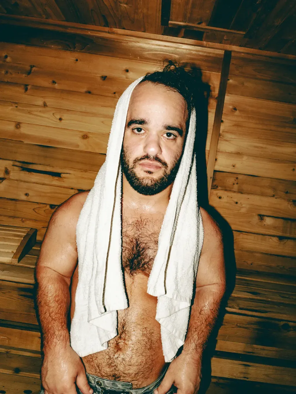 Close portrait of a guest with a towel over his head in the cedar Finnish sauna at Sauna Culture Charlotte