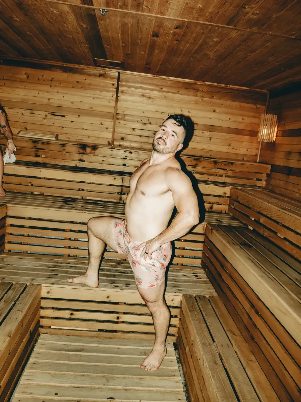 Guest in the tiered cedar Finnish sauna at Sauna Culture Charlotte looking back toward the camera