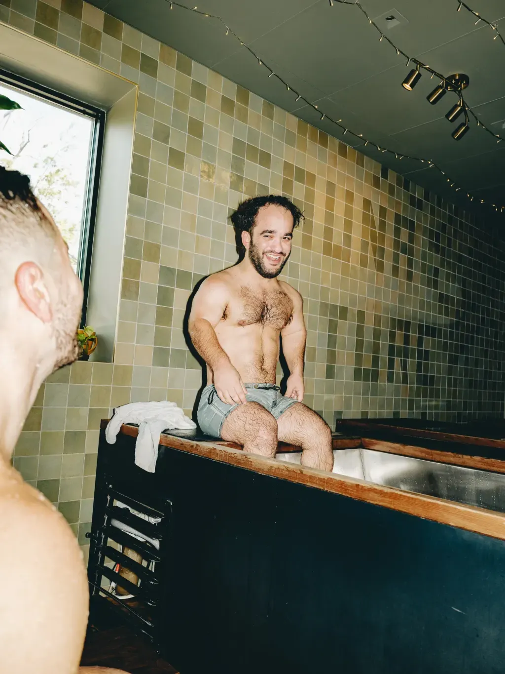 Guest smiling from the edge of an individual cold plunge at Sauna Culture in Cotswold, Charlotte
