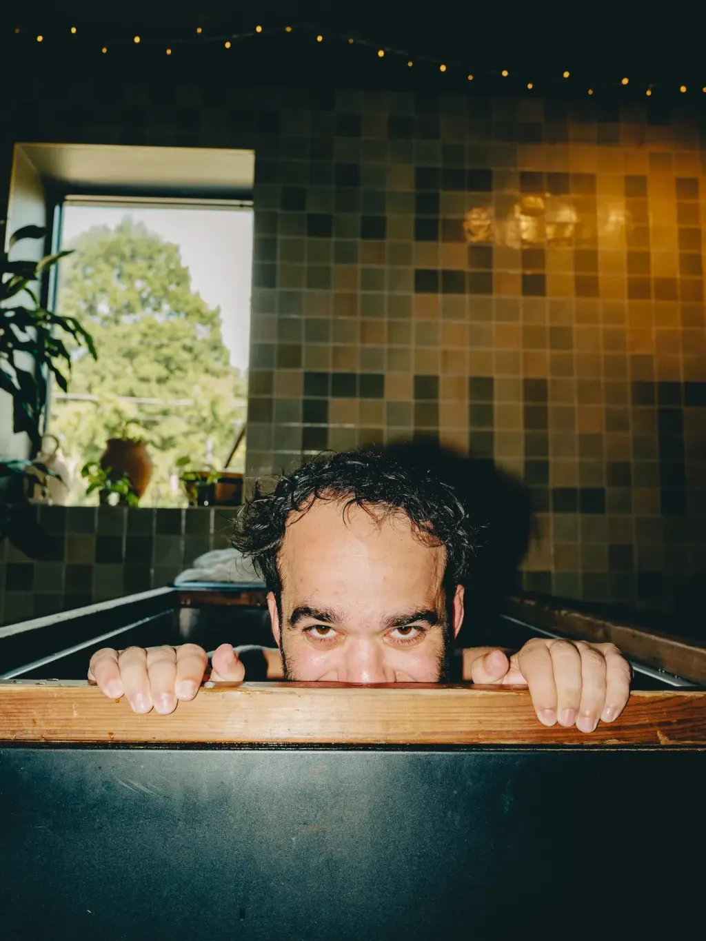 Guest peeking over the wooden rim of an individual cold plunge at Sauna Culture Charlotte
