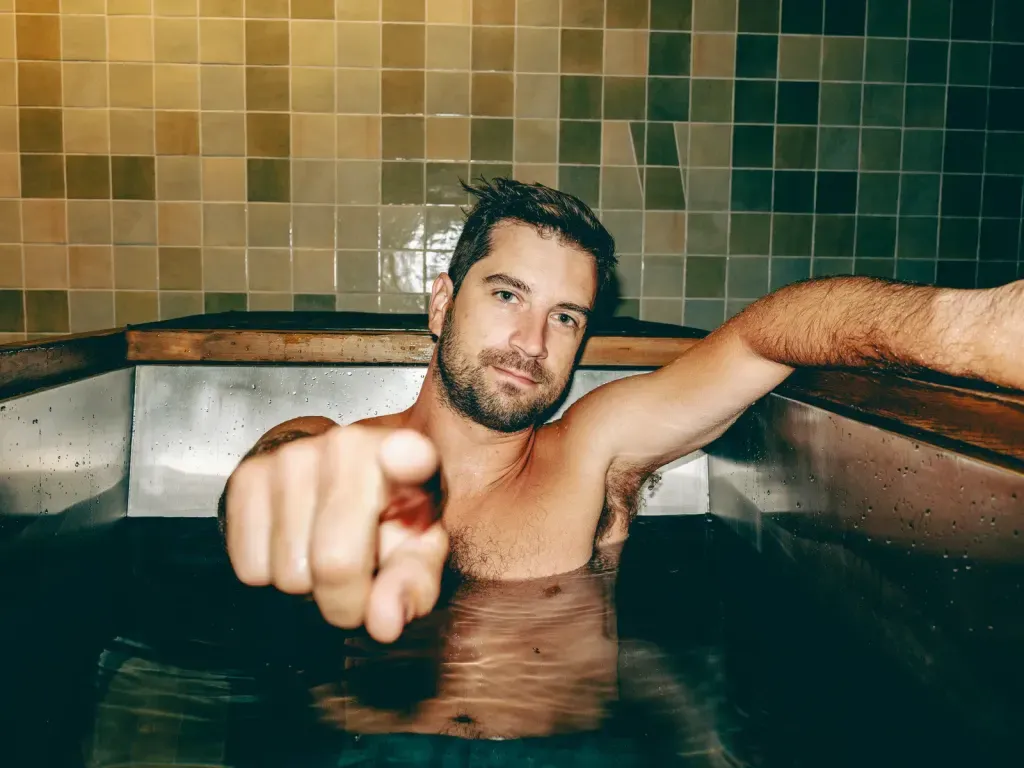 Guest pointing toward the camera from an individual stainless-steel cold plunge at Sauna Culture Charlotte