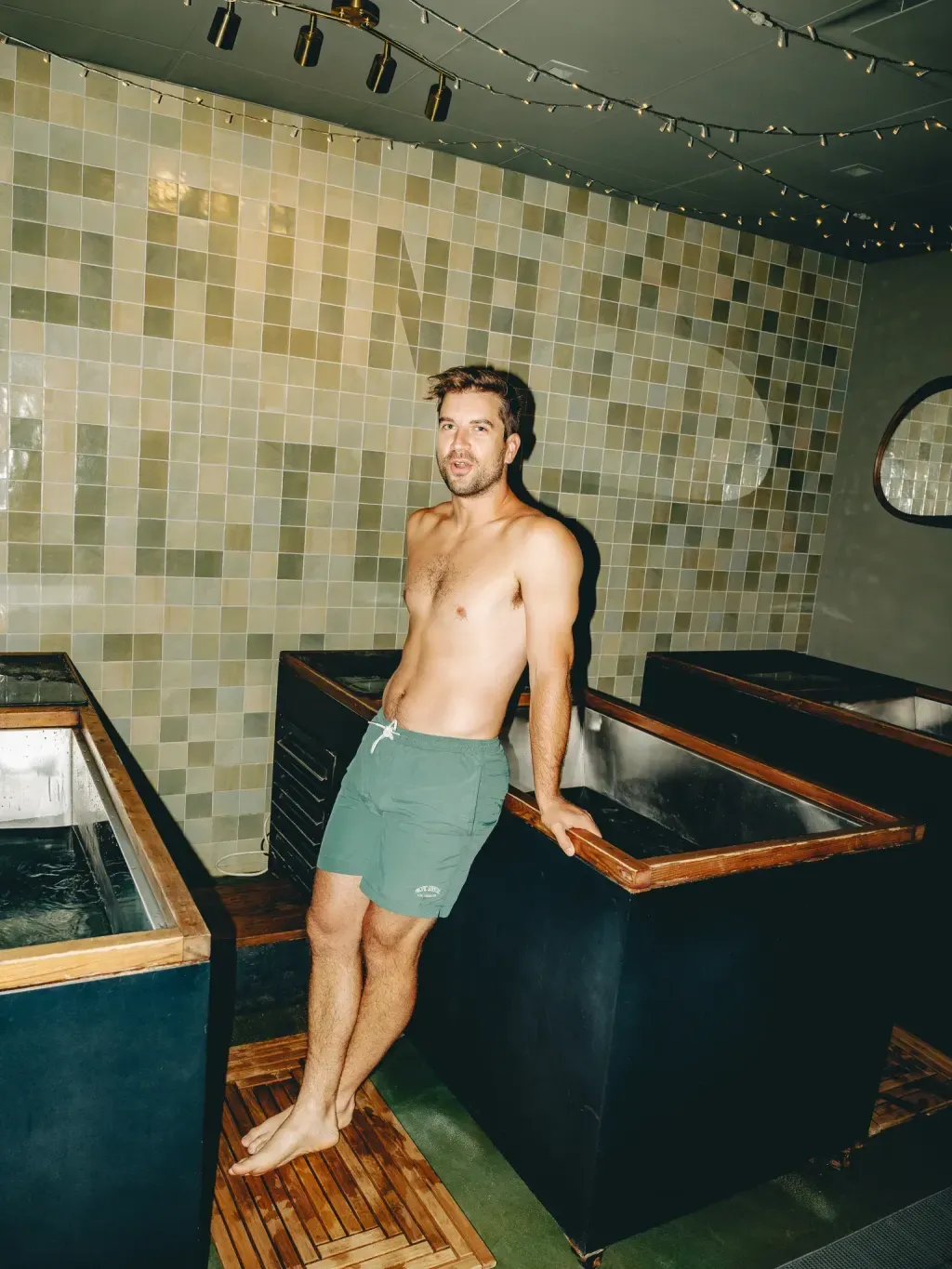 Guest leaning on an individual cold plunge in front of the Sauna Culture tile wall in Charlotte