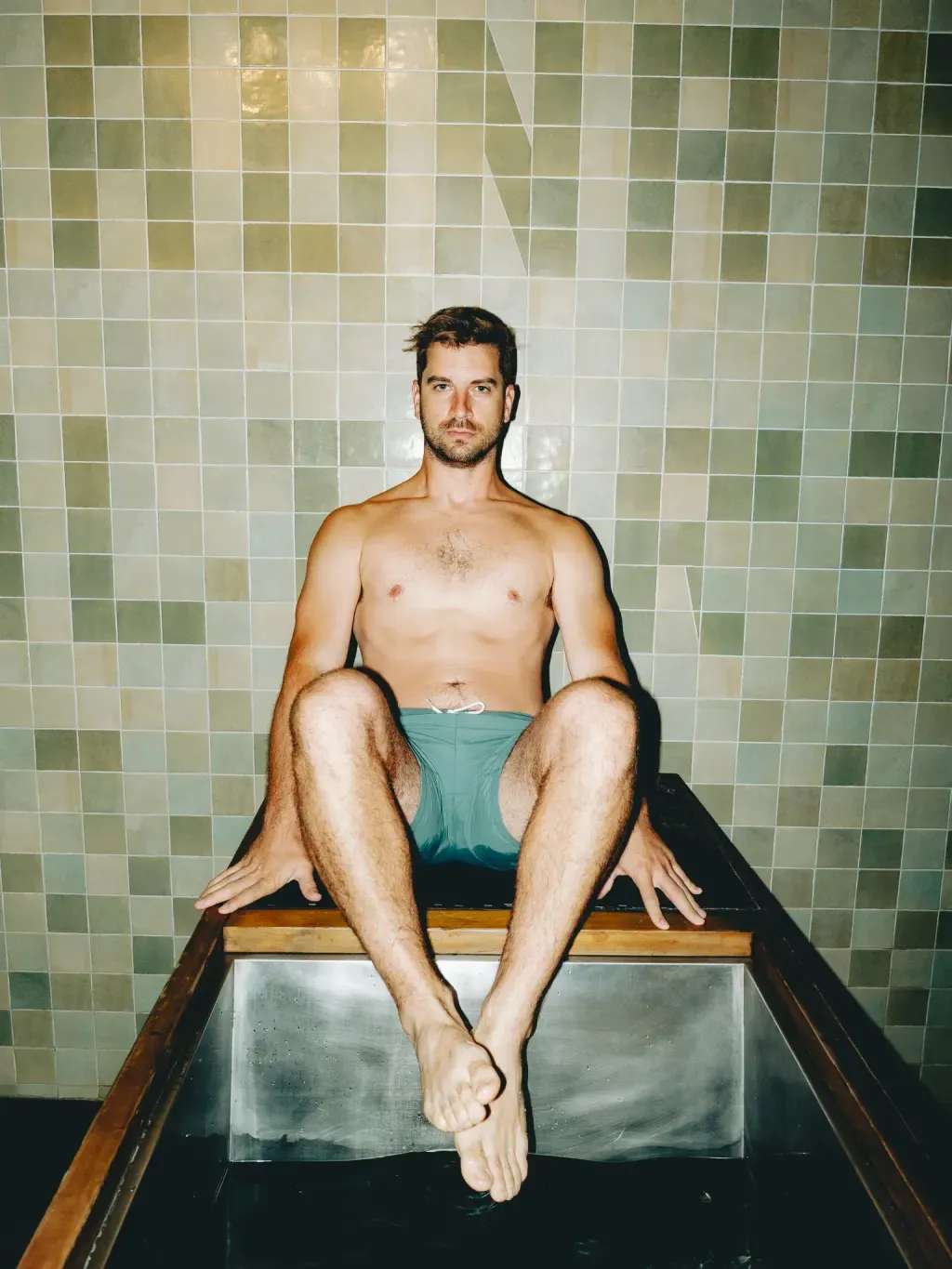 Guest sitting on the edge of an individual stainless-steel cold plunge at Sauna Culture Charlotte