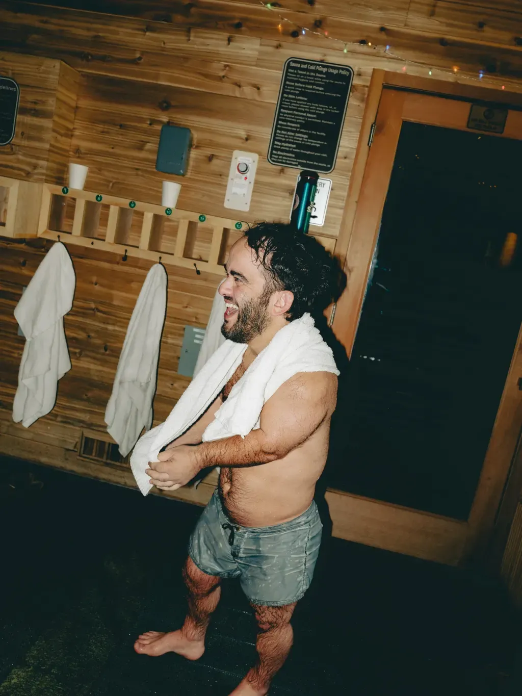 Guest laughing with a towel around his neck in the locker alcove at Sauna Culture Charlotte