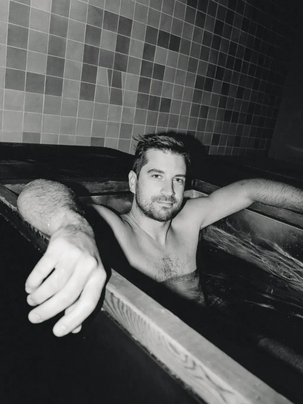 Black-and-white portrait of a guest chest-deep in an individual cold plunge at Sauna Culture Charlotte