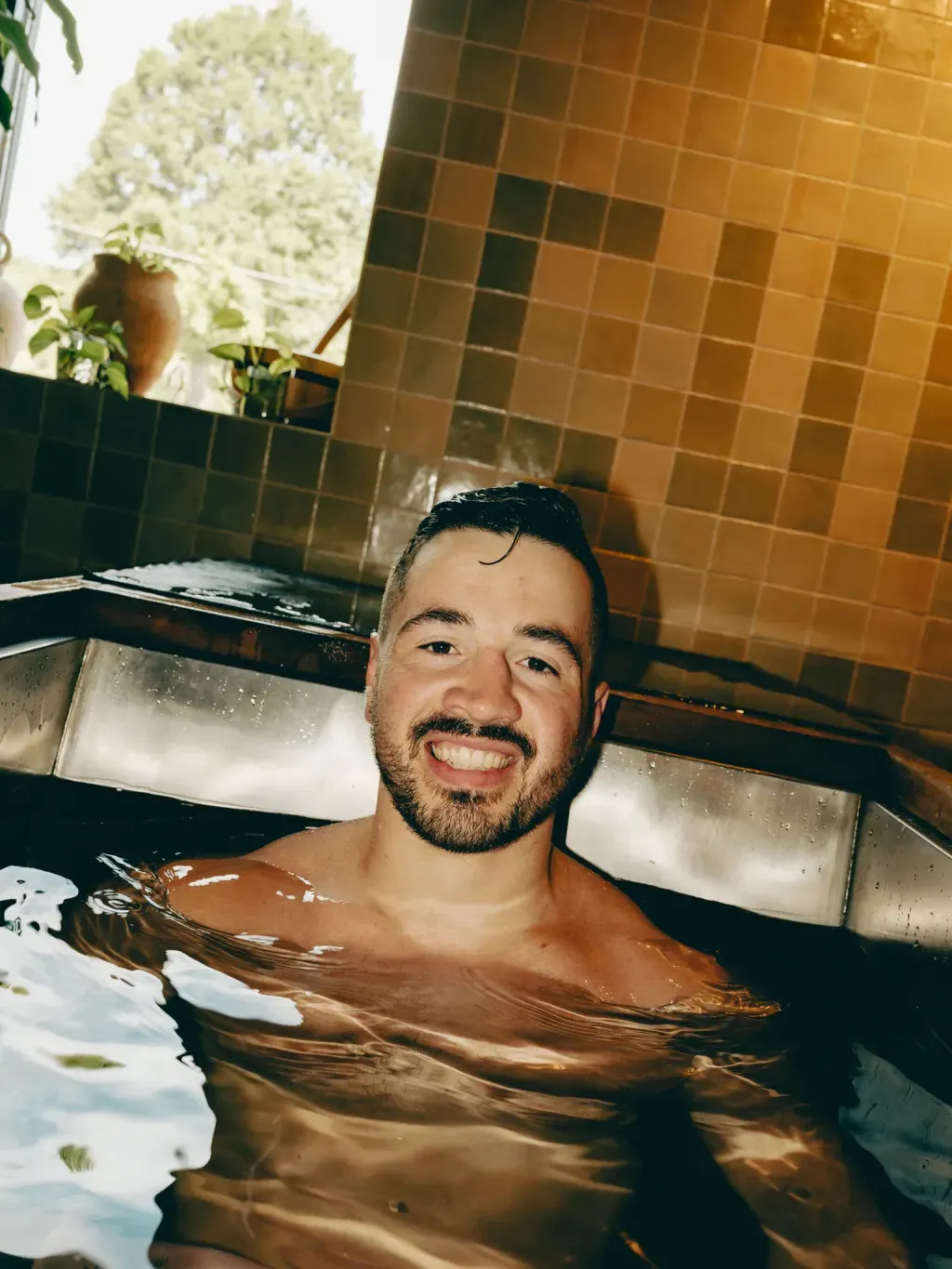Guest smiling chest-deep in an individual cold plunge at Sauna Culture Charlotte