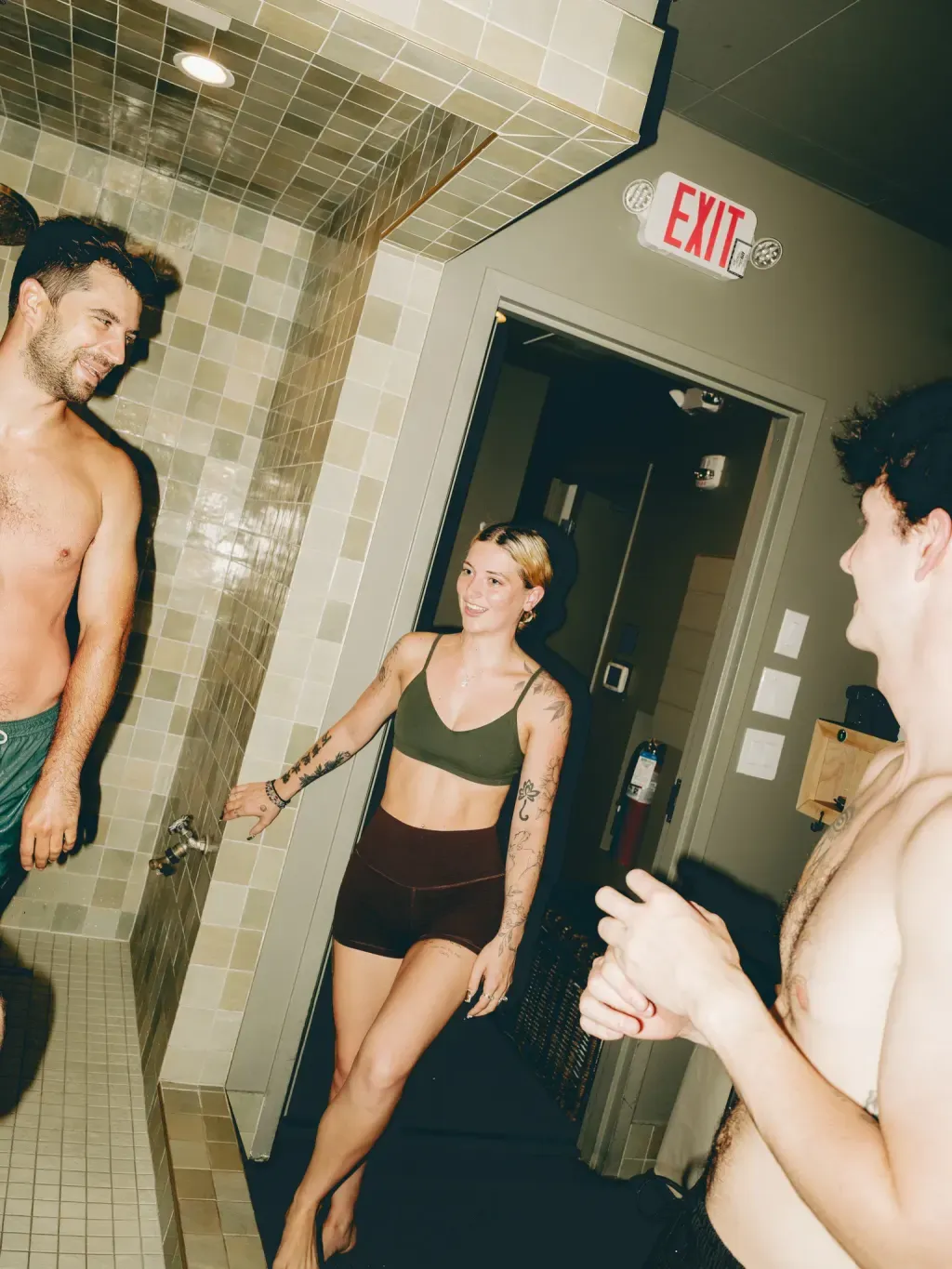 Friends talking by the rinse shower between contrast-therapy rounds at Sauna Culture Charlotte