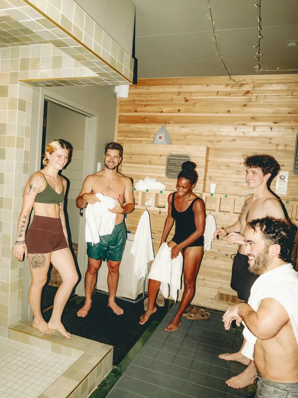 Five friends smiling in the cedar changing room at Sauna Culture Charlotte