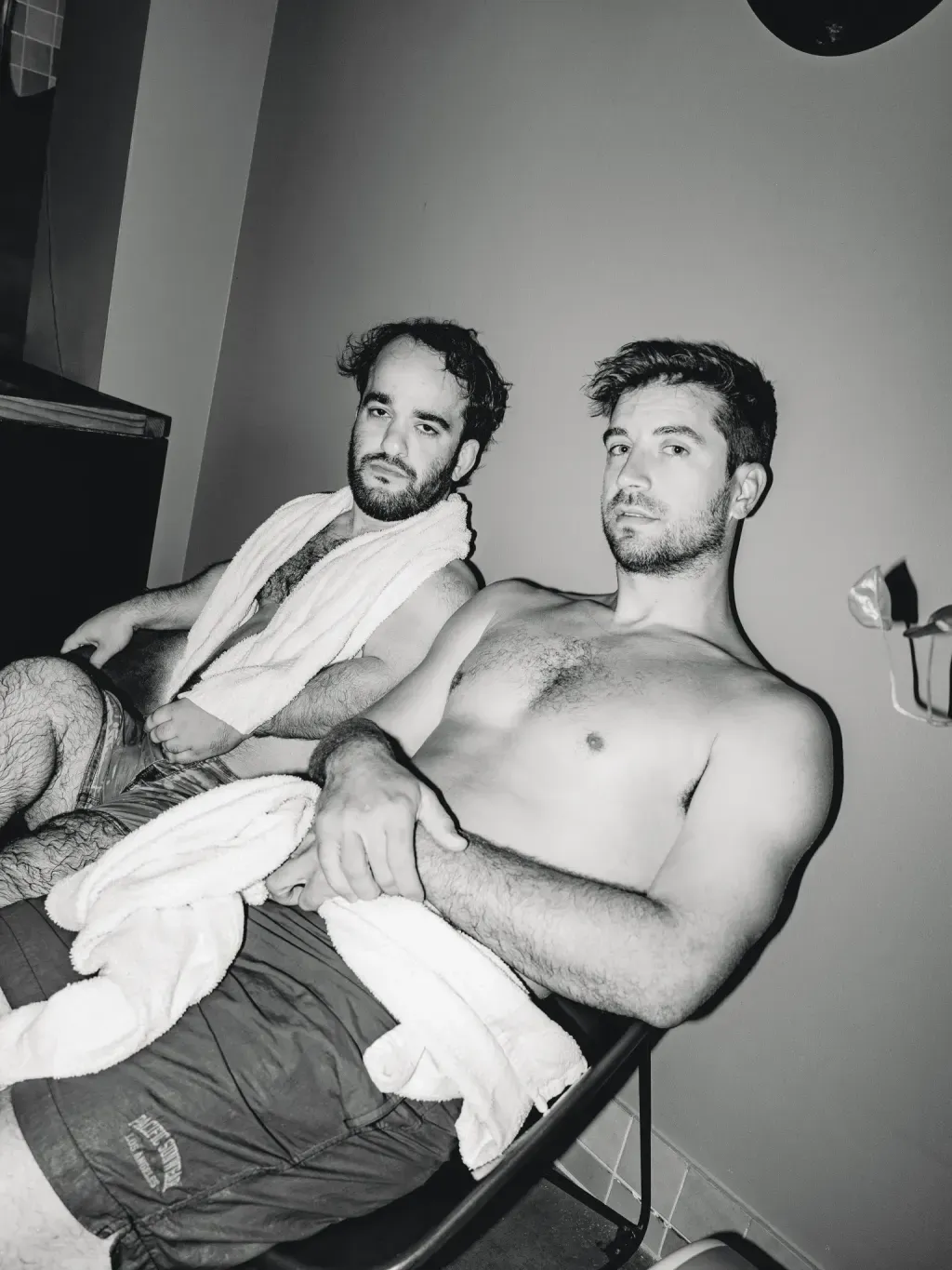 Black-and-white portrait of two guests resting with towels in the lounge at Sauna Culture Charlotte