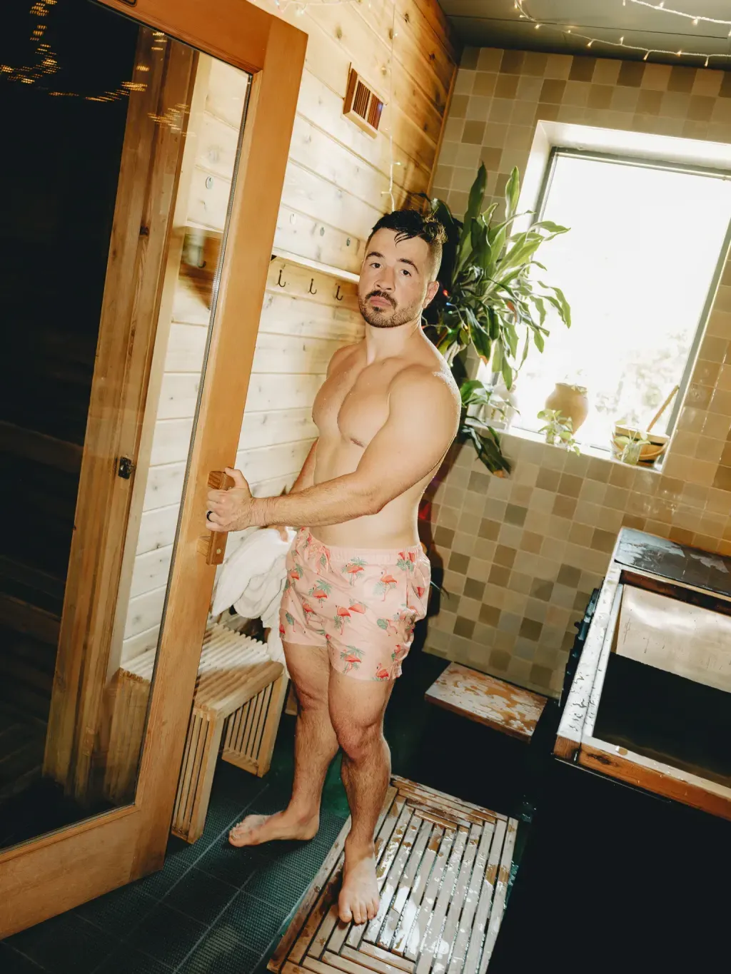 Guest at the open Finnish sauna door beside an individual cold plunge at Sauna Culture in Cotswold, Charlotte