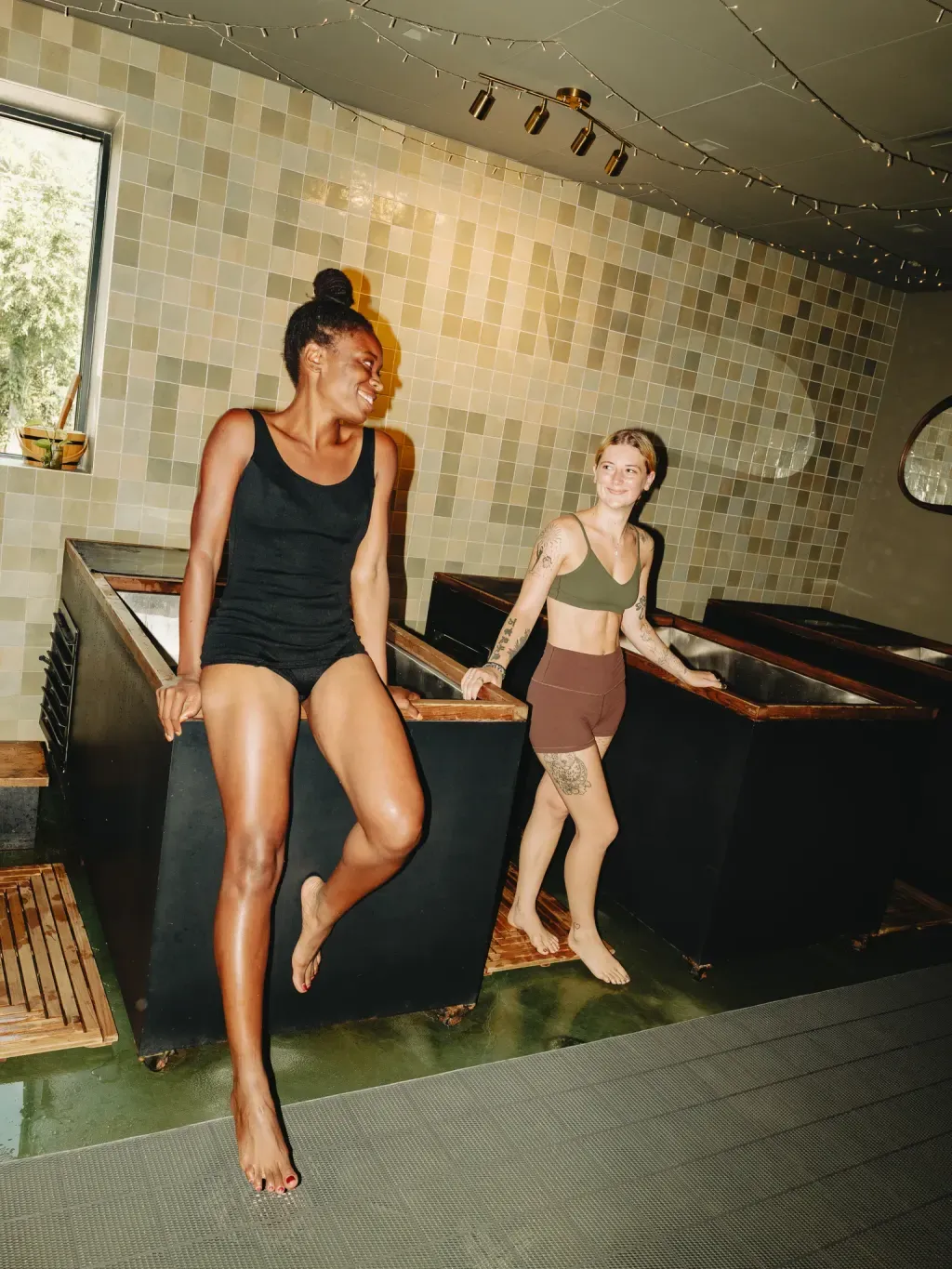 Two guests talking beside the individual cold plunges at Sauna Culture Charlotte