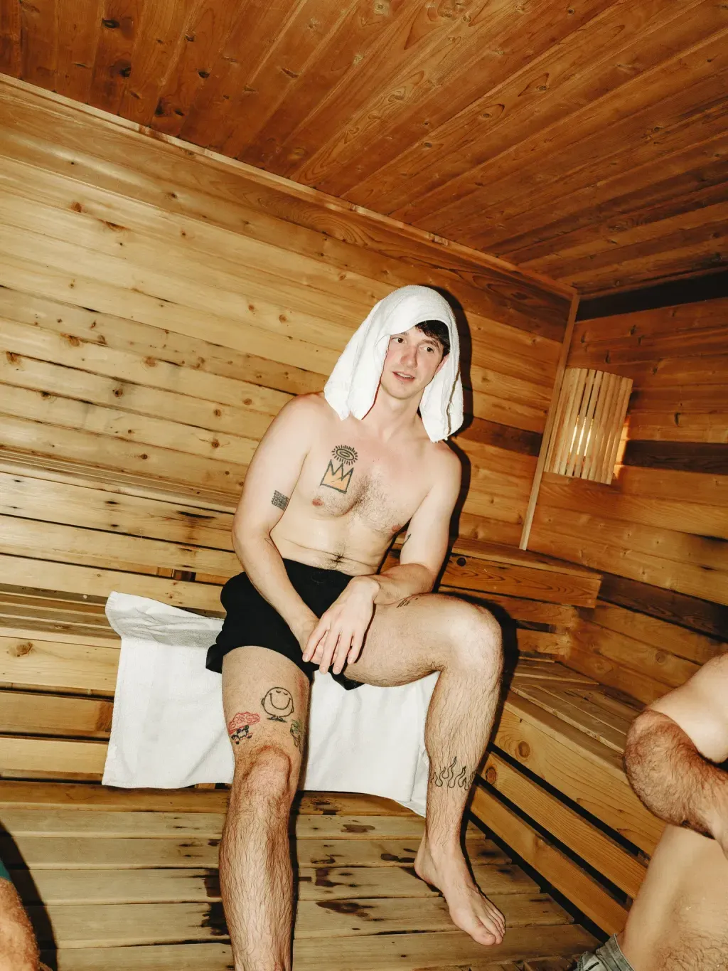 Guest with a towel over his head on a cedar bench in the Finnish sauna at Sauna Culture Charlotte