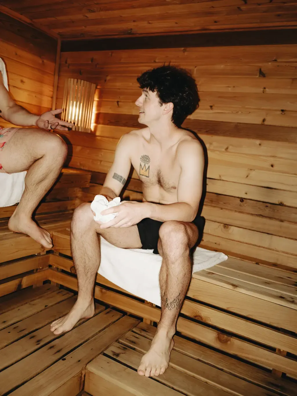 Guest talking on a cedar bench inside the traditional Finnish sauna at Sauna Culture Charlotte