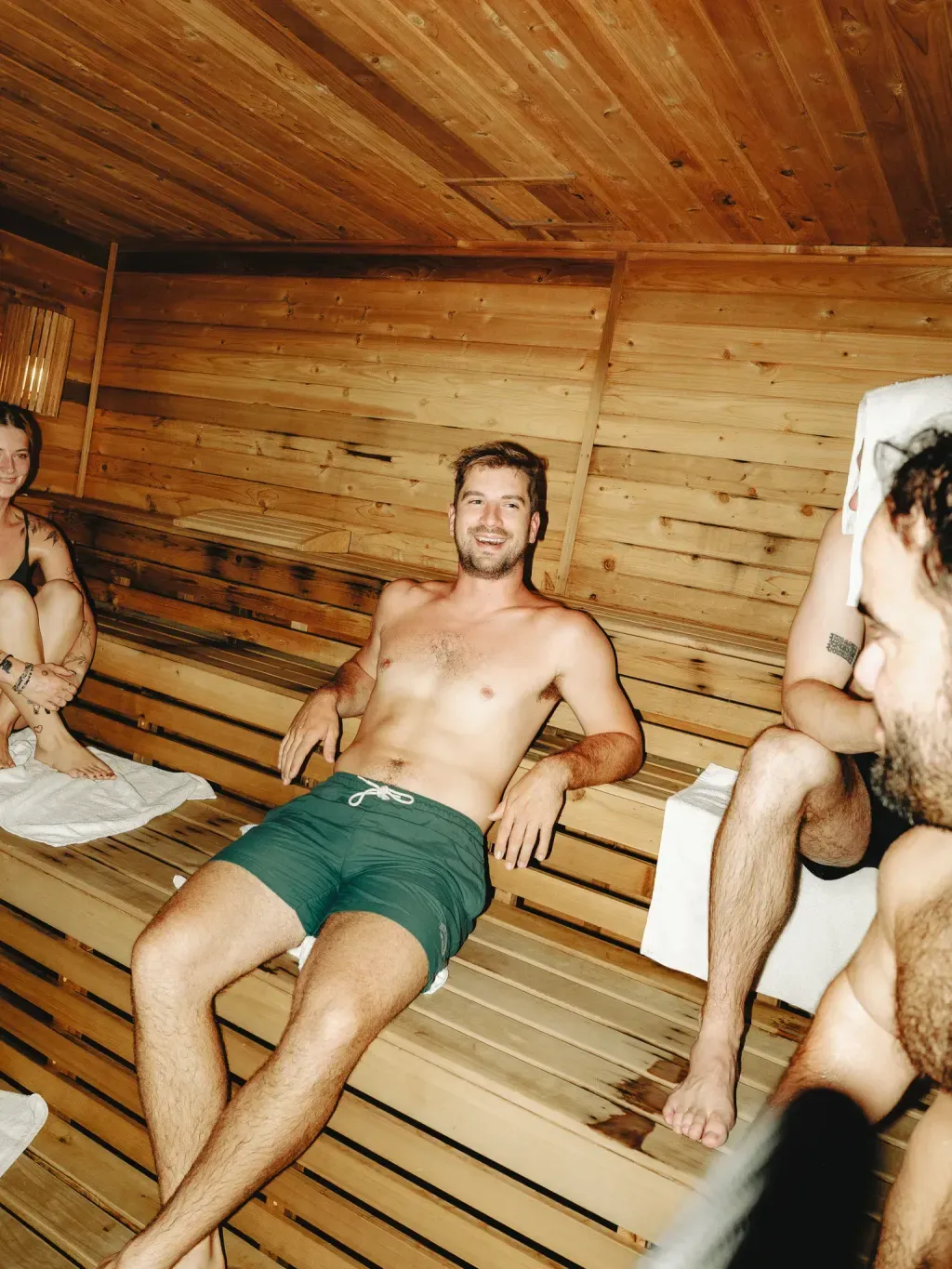Friends talking across the cedar benches of the Finnish sauna at Sauna Culture Charlotte