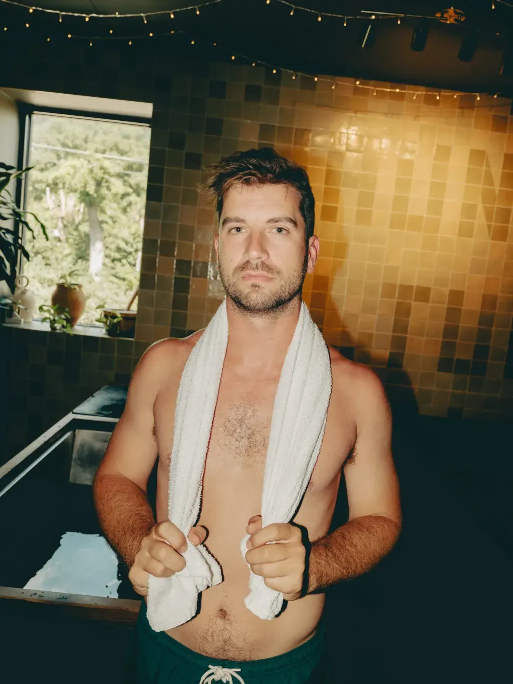 Guest with a towel around his neck beside an individual cold plunge at Sauna Culture Charlotte