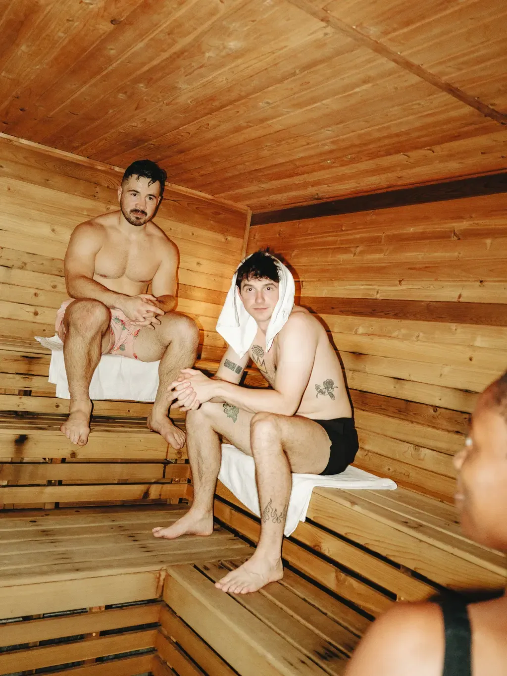 Three guests sharing tiered cedar benches in the Finnish sauna at Sauna Culture in Charlotte