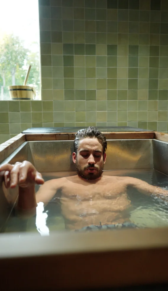 Guest soaking in a single individual cold plunge at Sauna Culture Charlotte