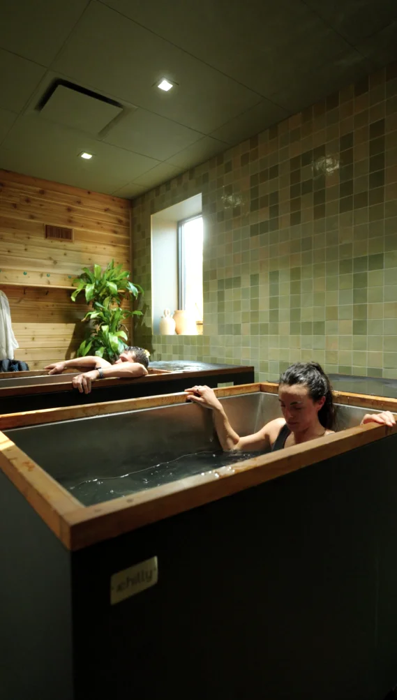 Two guests using neighboring individual cold plunges at Sauna Culture in Charlotte, NC