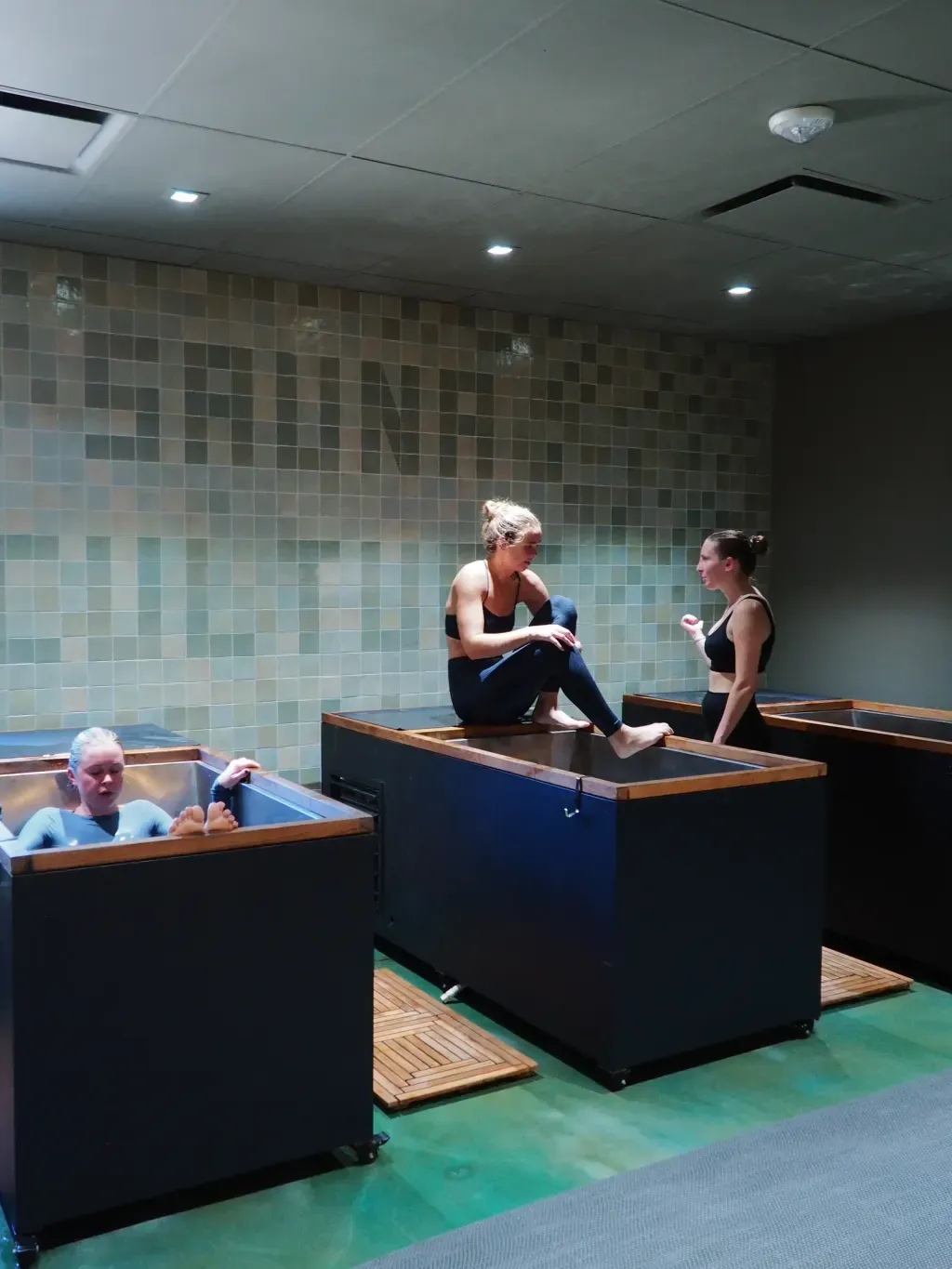 Friends in the rinse-down shower area between contrast-therapy rounds at Sauna Culture Charlotte